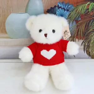Cute white plush teddy bear wearing a red knitted sweater with white heart pattern for kids gift