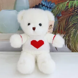 Cute white plush teddy bear wearing a red heart knit sweater soft stuffed animal toy gift.