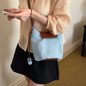 Women denim bucket bag casual crossbody shoulder bag with contrast brown flap and stylish design.