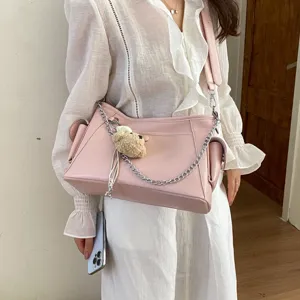 Stylish pink leather shoulder bag with chain strap, side pockets and cute bear pendant for women.