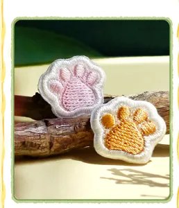 Close up detail shot of cute cat paw embroidered patches, fine stitching and vibrant colors.