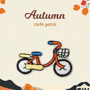 Close-up detail of cute autumn bicycle embroidered cloth patch with vibrant colored threads.