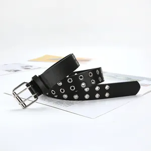 Detail view of a black leather double grommet punk belt with silver metal double buckles.