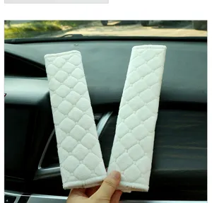 Detail shot of white plush car seat belt shoulder pads, soft diamond pattern cover for auto interior.