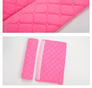 Pink plush car seat belt shoulder pad detail showing soft diamond pattern texture clearly.