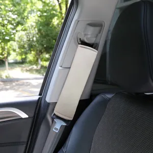 Close-up detail view of a soft beige car seat belt cover installed on a vehicle seat strap.