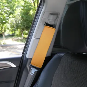 Close-up detail of soft yellow plush car seatbelt shoulder pad installed on car seat.