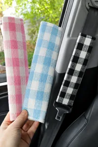 Detail view of soft plaid car seat belt shoulder pad, breathable fabric interior accessory.