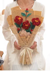 Handgefertigter Häkel-Kamelien-Blumenstrauß im Vintage-Zeitungspapier mit dekorativer Schleife.