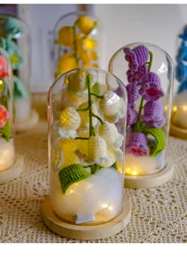 Close-up of handmade crochet lily of the valley night light in glass dome with warm LED.