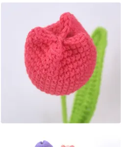 Close-up detail of handmade crochet yarn tulip flower, pink petal and green leaf design.