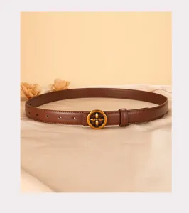 Detail view of brown leather belt with gold four-petal flower metal buckle texture.