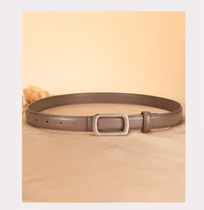 Minimalist brown leather belt detail, featuring a sleek silver metal buckle on elegant fabric.