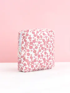 Gros plan d'une jolie trousse de maquillage carrée à fleurs, détail de petite pochette.