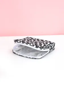 Vue detaillee de la pochette de rangement pour serviettes hygieniques a fleurs noir et blanc.