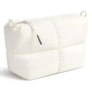 Close-up detail of the white quilted puffer cosmetic bag showing soft texture and fine zipper.