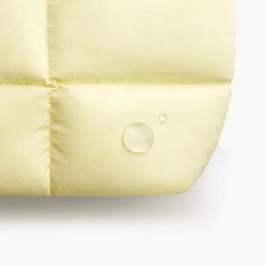 Close-up detail of soft yellow quilted waterproof fabric material, showing smooth texture.