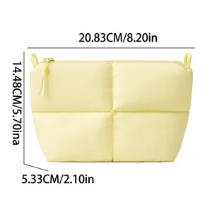 Puffer quilted cosmetic bag detail view, soft yellow makeup pouch with zipper closure.
