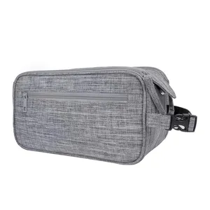 Detalle del neceser de viaje gris con bolsillo frontal con cremallera y asa de hebilla lateral.