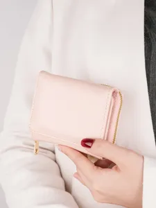 Elegant women's pink trifold wallet with zipper coin pocket and compact card holder design.