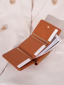 Brown women's leather tri-fold wallet detail showcasing card slots and zipper coin pocket.
