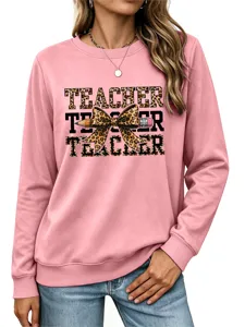 Primer plano detallado de la sudadera rosa de maestra con lazo de leopardo y lápiz.
