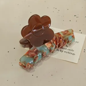 Nahaufnahme einer stilvollen französischen Acetat Haarklammer mit brauner Blume und buntem Muster.