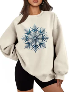 Close-up van een gezellige beige sweater met een opvallend blauw glitter sneeuwvlokmotief.
