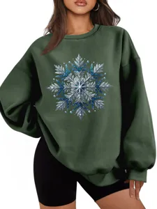 Detailopname van het glinsterende blauwe en zilveren sneeuwvlokmotief op de groen sweater.