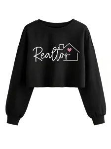 Detalle de cerca de la sudadera crop negra con texto Realtor blanco y corazón rosa.