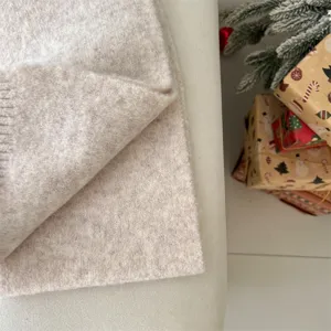Detailed close-up of soft beige knit fabric for winter scarf, cozy seasonal product texture display.