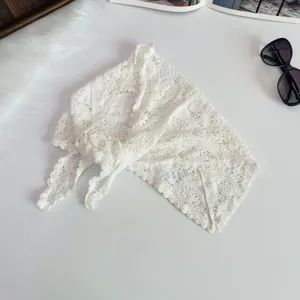 Detail view of the white crochet lace triangle scarf, showing delicate hollow knit pattern and texture.