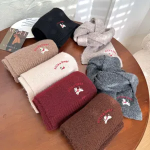 Detail of colorful knitted kids scarves featuring cute puppy embroidery and soft warm fabric.