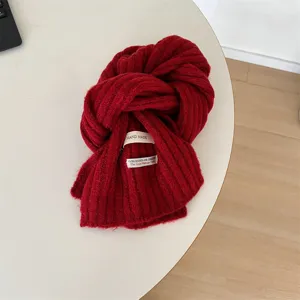Closeup of soft red knitted children winter scarf with handmade fabric label detail.