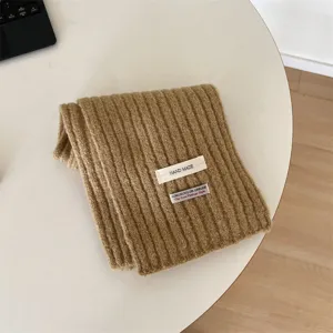 Detailed view of cozy brown knitted winter scarf for kids, featuring handmade fabric label.