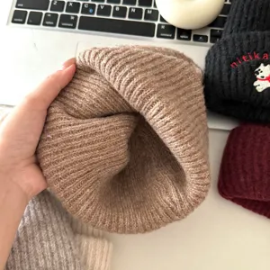 Close-up detail of soft brown knitted winter beanie hat for kids, showing warm ribbed texture.