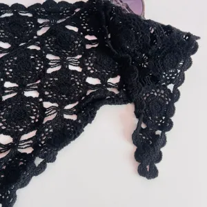Close-up of black crochet lace triangular scarf, fine knit texture detail for women.
