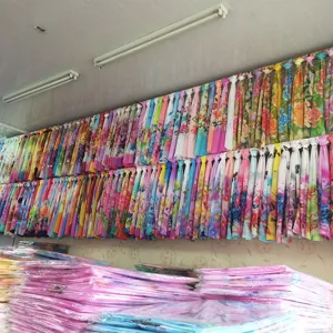 Factory detail view showing hanging colorful floral chiffon scarves and beach shawls.