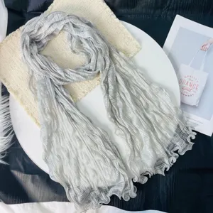 Close-up view of a light grey crinkled gauze scarf, breathable summer long wrap shawl detail.