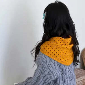 Vista detallada de una bufanda triangular de punto calado amarillo para niños de espaldas.
