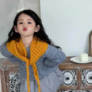 Detalle de bufanda triangular de punto calado para niños, cuello amarillo accesorio otoño.