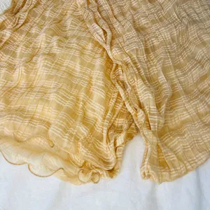 Close-up detail of pleated striped scarf fabric showing soft texture and lettuce edge.