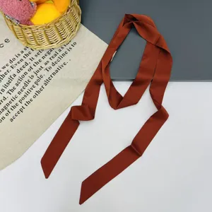 Detail view of a solid color narrow silk scarf, perfect as a bag ribbon or stylish hair band.