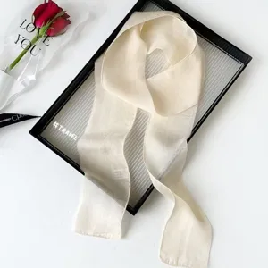 Detailed view of a lightweight beige long skinny scarf, elegant ribbon for hair and bags.