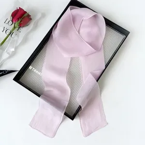 Closeup detail of the elegant light pink solid color long ribbon silk scarf for women styling.