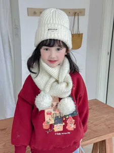 Cute kids knitted winter scarf with pom poms and matching beanie hat detail shot.