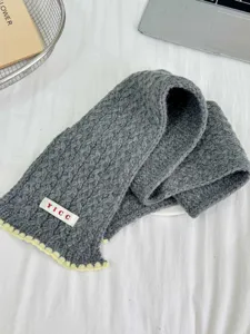 Close-up detail of the cozy gray cable-knit children scarf featuring cute yellow wavy edges.