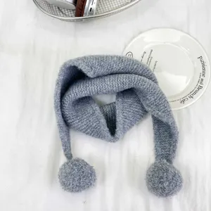 Detail view of grey knitted kids neck warmer with cute pom-poms, soft winter scarf close-up.