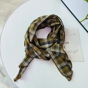Detailed shot of vintage plaid skinny scarf, retro green pattern neckerchief, delicate edge.