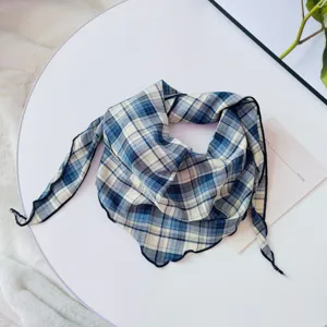Detailed close-up of blue and white plaid scarf, showing soft fabric texture and delicate drape.